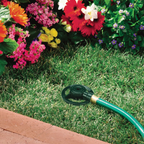 Dad's reliable zinc spot sprinkler connected to a garden hose, lying on grass and surrounded by beautiful flowers.