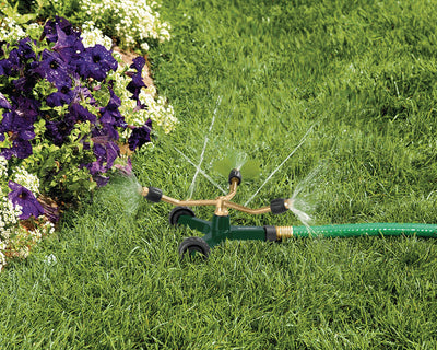 Brass 3-Arm Adjustable Sprinkler with Wheel Base watering lawn. 