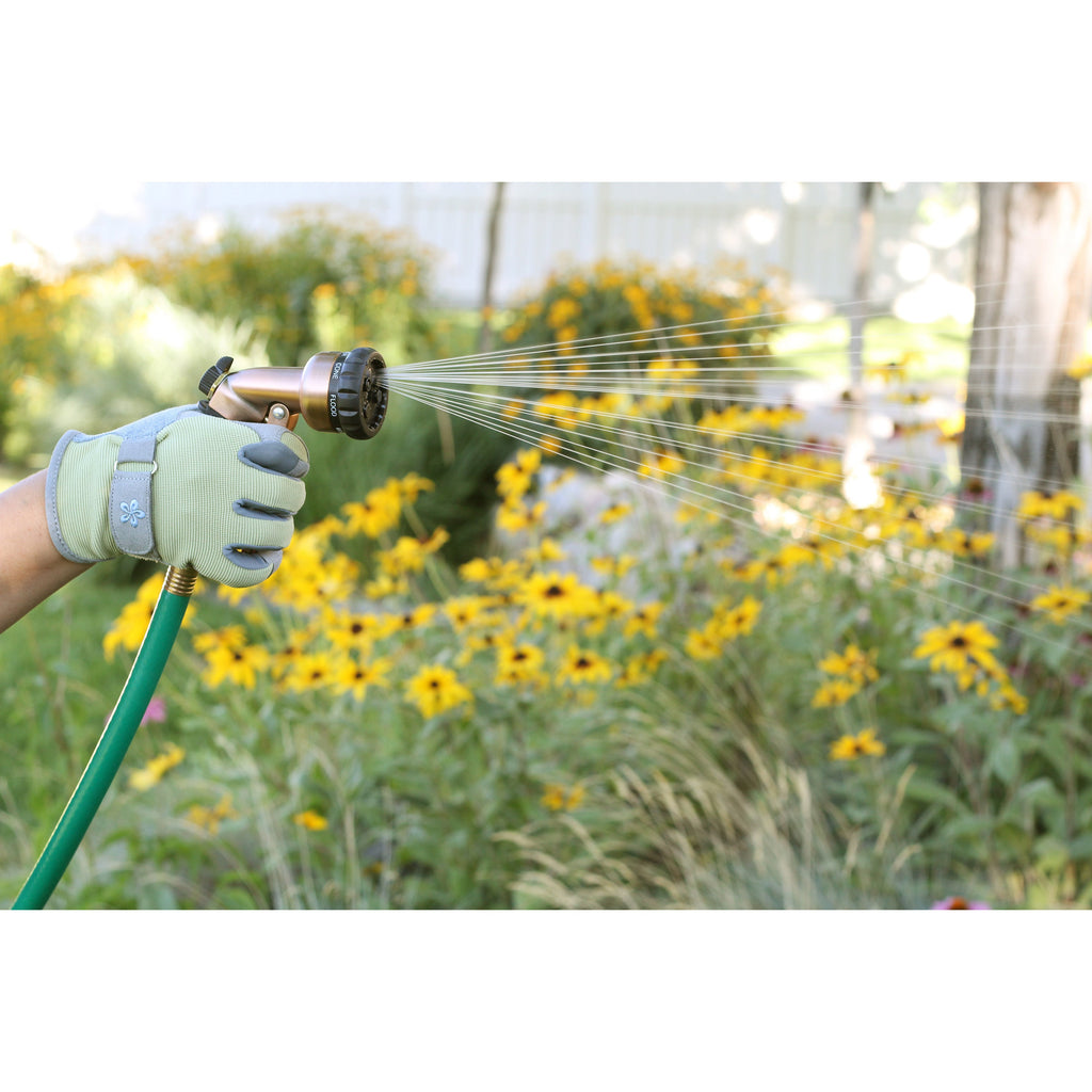 Person watering yellow flowers with a garden hose and spray nozzle.